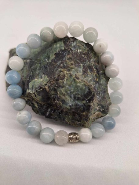 Bracelet en perles d'agate bleue et blanche sur un fond rocheux.