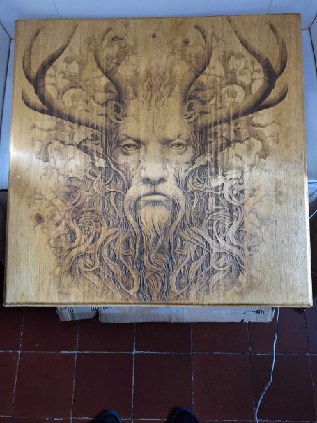 Illustration d'un visage avec des cornes, en relief sur un fond doré.